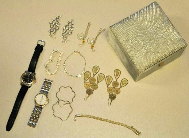Verschiedene Schmuckstücke, darunter Uhren, Armbänder und Ohrringe, liegen neben einer verzierten Schatulle.