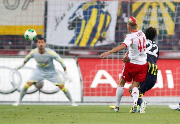 Ein Fußballspieler mit rotem Irokesenschnitt kämpft um den Ball, während der Torwart bereitsteht.