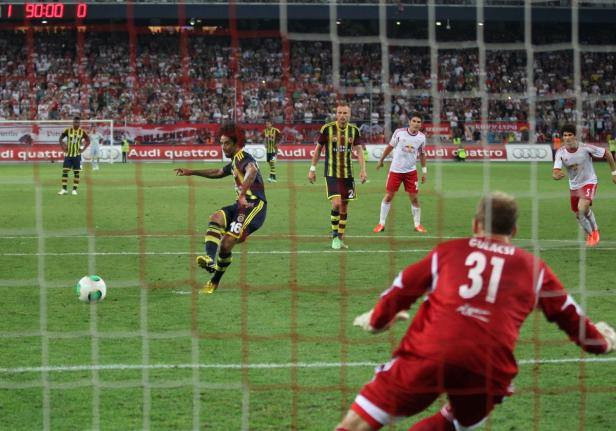 Ein Fußballspieler schießt den Ball, während der Torwart sich bereit macht, ihn abzuwehren.