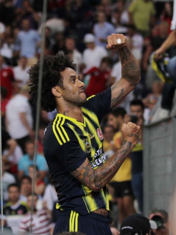 Ein Fußballspieler mit Tattoos jubelt vor einer Zuschauermenge.
