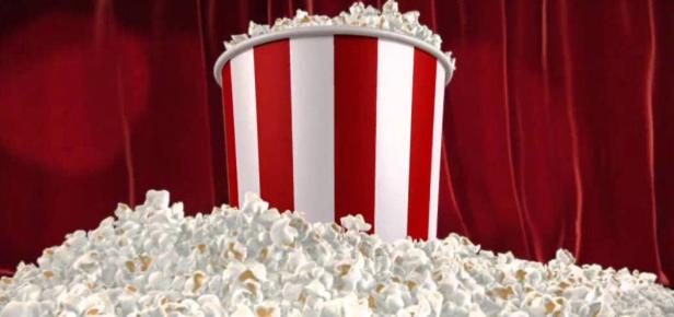 Ein rot-weiß gestreifter Popcorn-Eimer steht vor einem roten Vorhang.