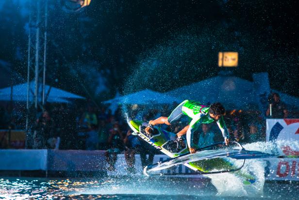 Ein Windsurfer springt mit seinem Board über das Wasser.