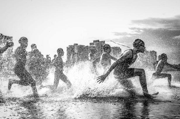 Triathleten laufen bei einem Wettkampf durch das Wasser.