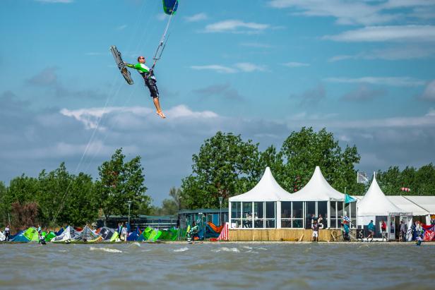 Ein Kitesurfer springt hoch in der Luft über dem Wasser.
