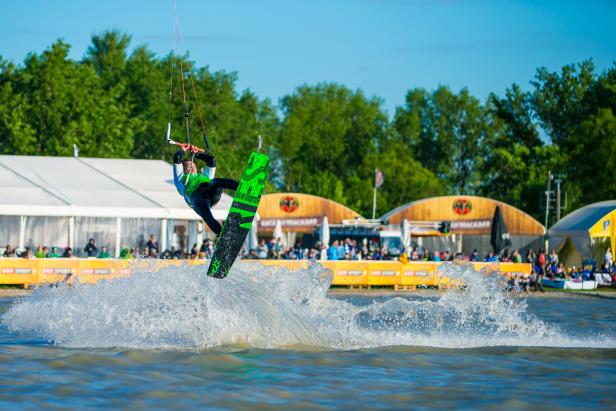 Ein Kitesurfer springt mit seinem Board über das Wasser.
