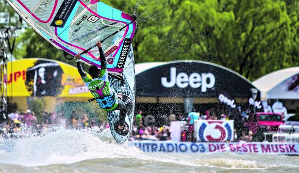 Ein Windsurfer springt mit seinem Surfbrett über das Wasser.