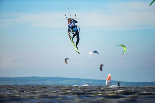 Eine Kitesurferin springt mit ihrem Board in der Luft.