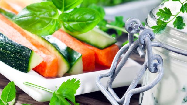 Gemüsesticks mit Karotten, Zucchini und Gurke werden mit einem Kräuterdip serviert.