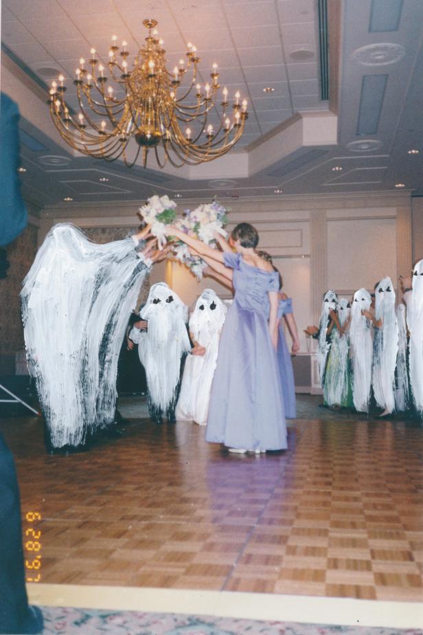 Bräute in lila Kleidern werfen Brautsträuße in eine Gruppe von als Geister verkleideten Personen.