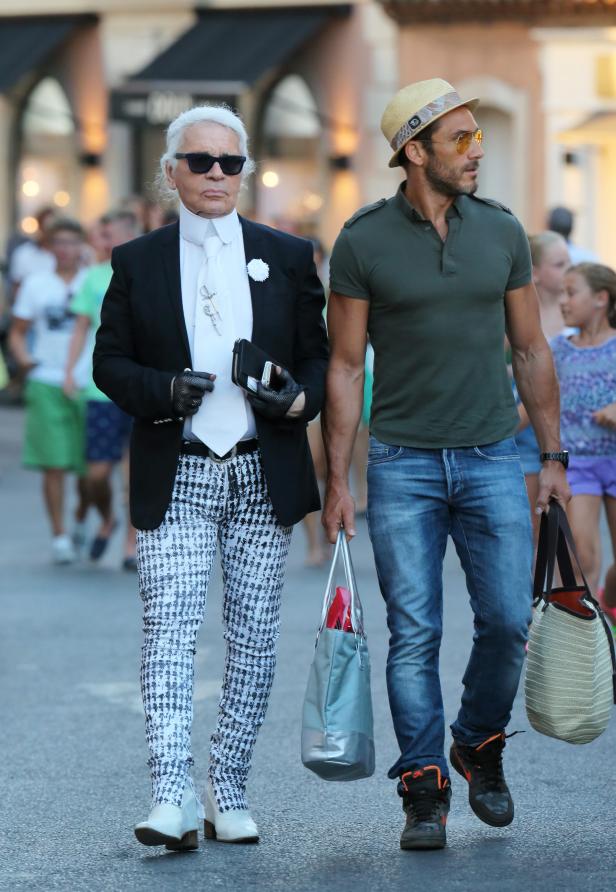 Karl Lagerfeld und ein Mann mit Hut gehen eine Straße entlang.
