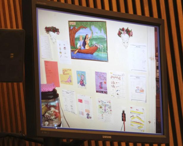 Ein Monitor zeigt eine Wand voller Kinderzeichnungen und ein Bild von Pocahontas.
