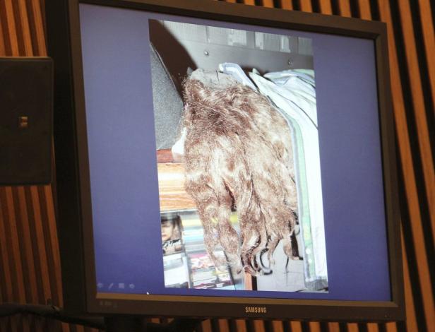 Ein Monitor zeigt ein Foto von einer Perücke und einigen DVDs in einem Schrank.