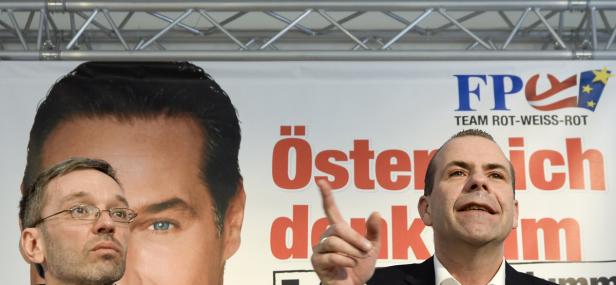 Zwei Männer stehen vor einem FPÖ-Wahlplakat mit der Aufschrift „Österreich denkt anders“.