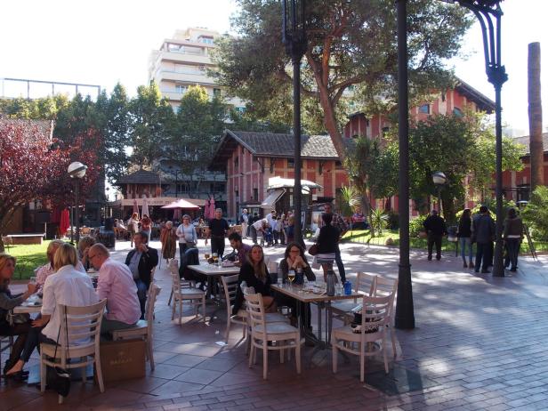 Menschen sitzen in einem Straßencafé und genießen das sonnige Wetter.