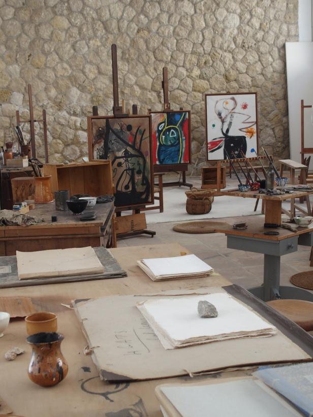 Das Atelier eines Künstlers mit Staffeleien, Tischen und unfertigen Gemälden.