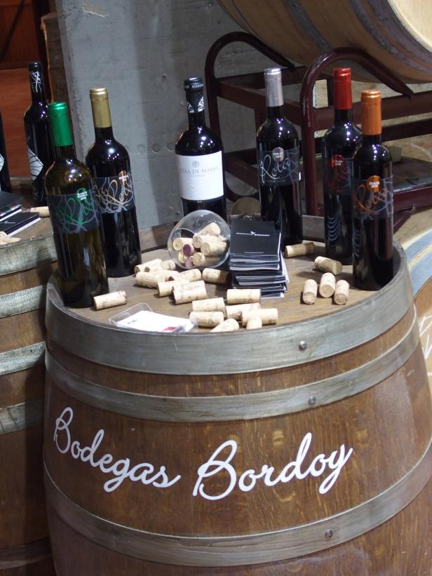 Mehrere Weinflaschen und Korken stehen auf einem Weinfass mit der Aufschrift „Bodegas Bordoy“.