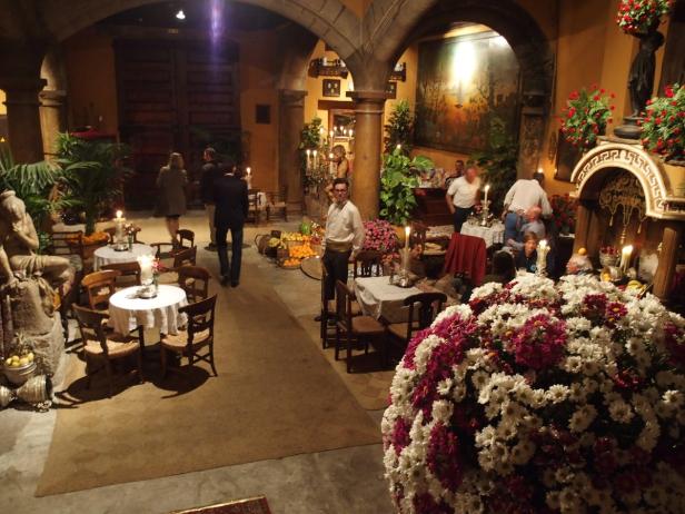 Ein Innenraum mit gedeckten Tischen, Blumenarrangements und mehreren Personen.