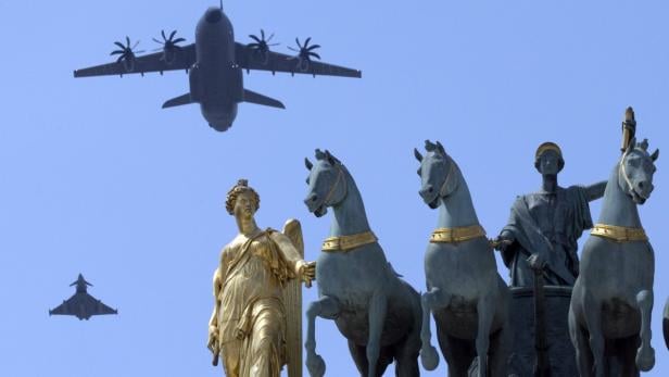 Ein Airbus A400M und ein Kampfjet fliegen über eine Quadriga-Statue.