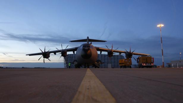 Ein Airbus A400M steht auf einem Flugfeld im Abendlicht.