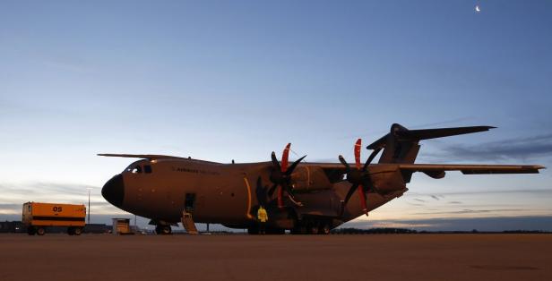 Ein Airbus A400M Militärtransporter steht auf einem Flugfeld bei Dämmerung.