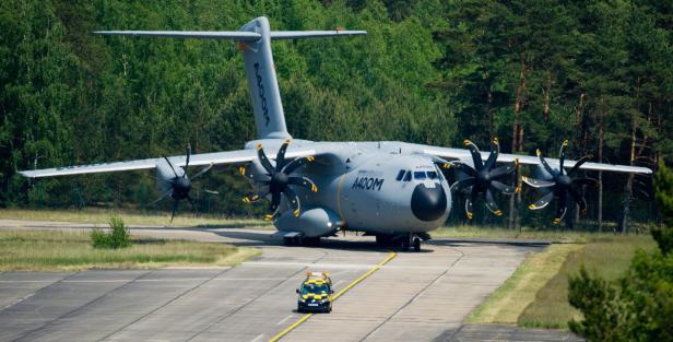 Ein Airbus A400M Transportflugzeug auf einer Startbahn mit einem Begleitfahrzeug.