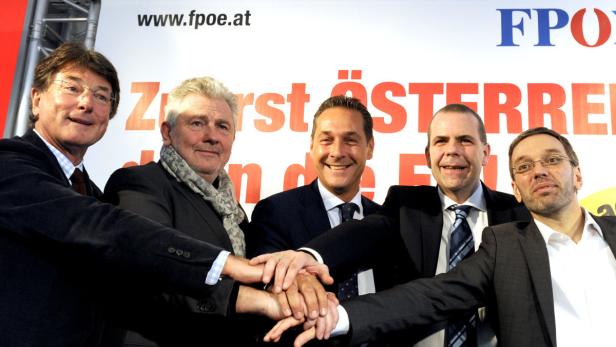 Fünf Männer in Anzügen legen ihre Hände übereinander vor einem FPÖ-Hintergrund.