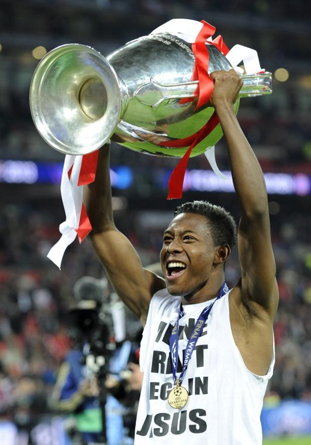 Ein jubelnder Fußballspieler hält den Champions-League-Pokal in die Höhe.