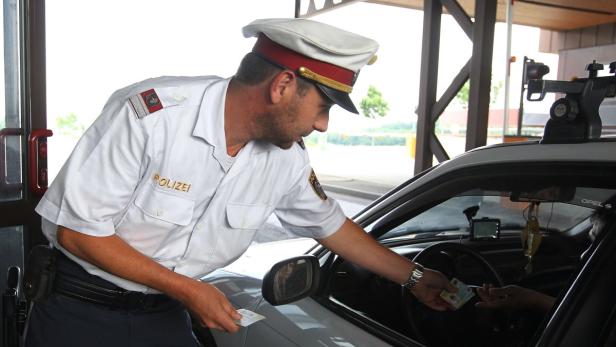 Ein österreichischer Polizist kontrolliert die Ausweispapiere eines Autofahrers.
