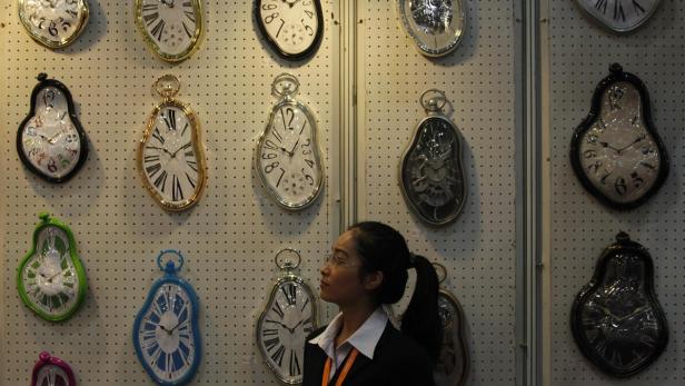 Eine Frau betrachtet eine Wand mit schmelzenden Uhren im Stil von Salvador Dalí.
