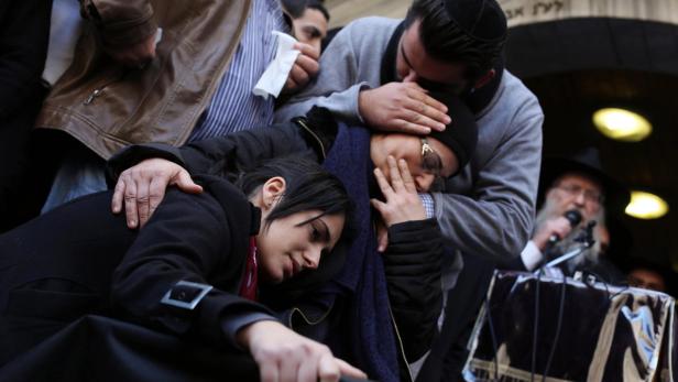 Trauernde Menschen umarmen sich bei einer Beerdigung.