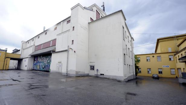 Ein großes, weißes Gebäude mit Graffiti an der Fassade und einem nassen Innenhof.