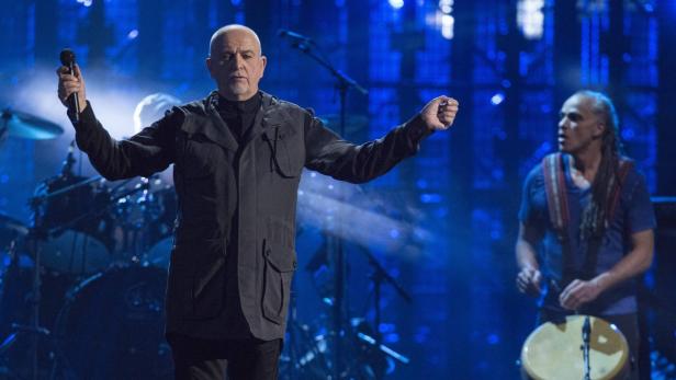 Peter Gabriel tritt mit einem Schlagzeuger auf einer Bühne auf.