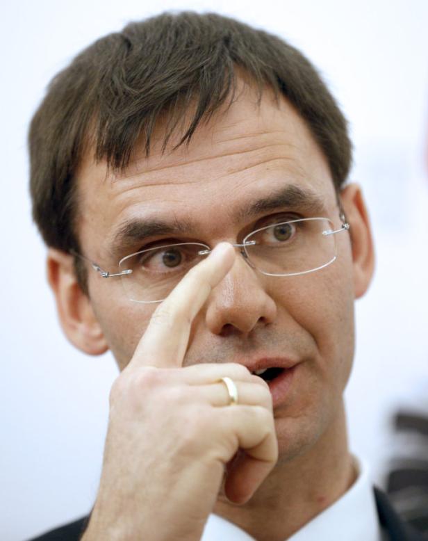 Ein Mann mit Brille berührt seine Nase mit dem Finger.