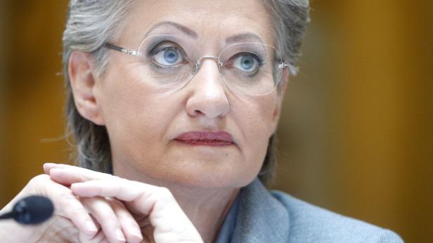 Eine Frau mit Brille und grauem Haar blickt nach oben.