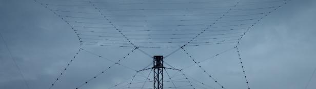 Eine große Drahtantenne vor einem bewölkten Himmel.
