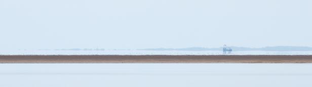 Eine Ölplattform ist am Horizont über dem Wasser zu sehen.