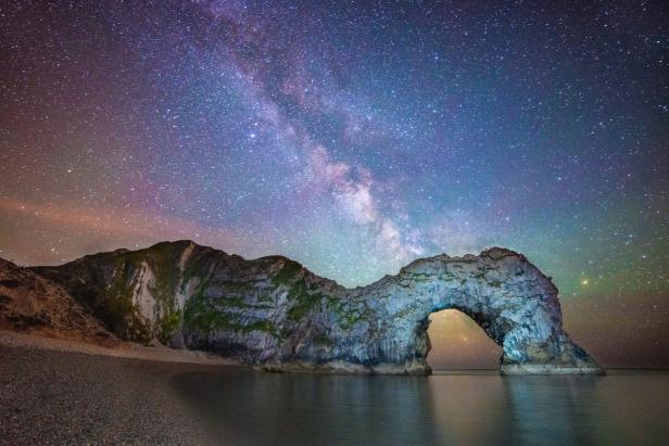 Die Milchstraße über dem Durdle Door Felsbogen in Dorset, England.