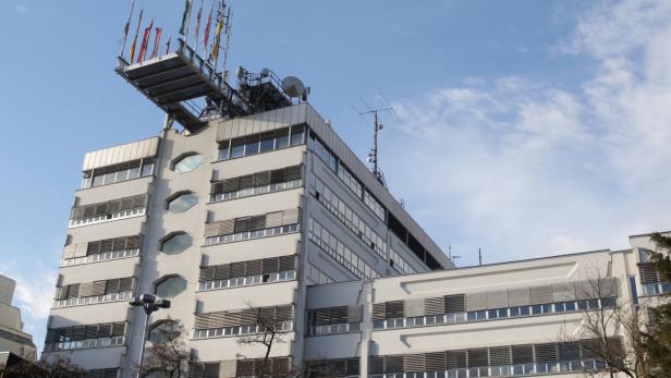 Ein hohes, weißes Gebäude mit Antennen und Flaggen auf dem Dach.
