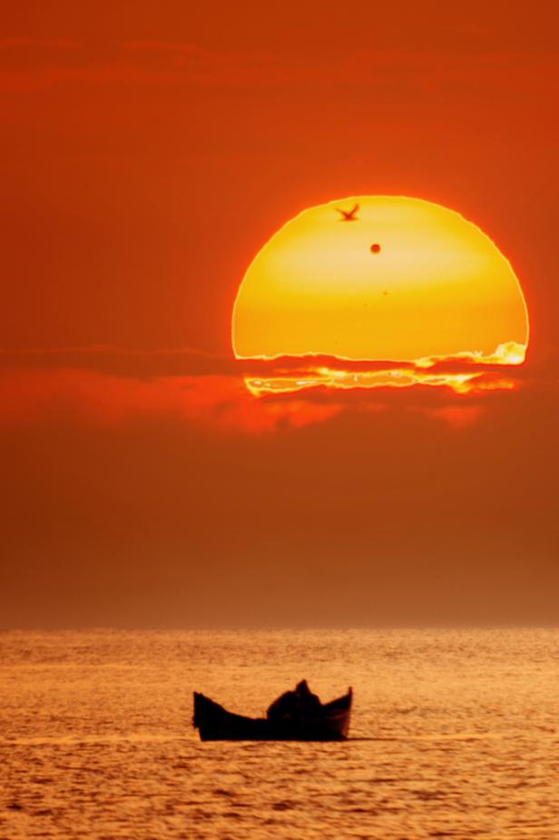 Ein kleines Boot fährt auf dem Meer, während die Sonne untergeht.