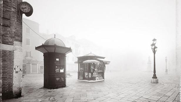 Ein nebliger Platz mit einem Kiosk und einer alten Straßenlaterne.