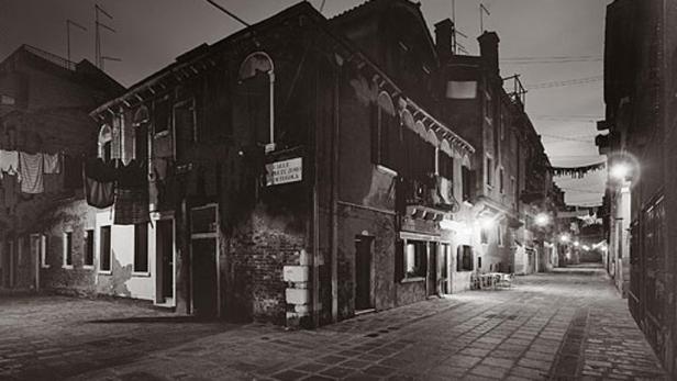Eine dunkle Gasse in Venedig mit Wäscheleinen zwischen den Häusern.