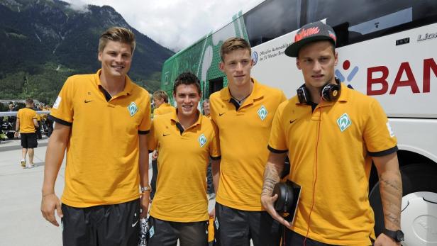 Eine Gruppe von Werder Bremen-Spielern posiert vor einem Mannschaftsbus.