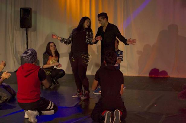 Ein Mann und eine Frau tanzen vor einem Publikum auf einer Bühne.