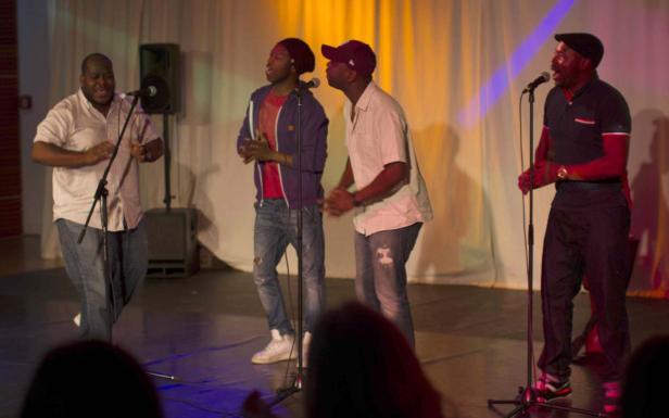 Eine Gruppe von vier Sängern tritt auf einer Bühne vor Publikum auf.