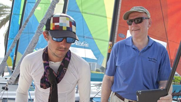 Zwei Männer stehen vor mehreren Hobie Cat-Segelbooten.
