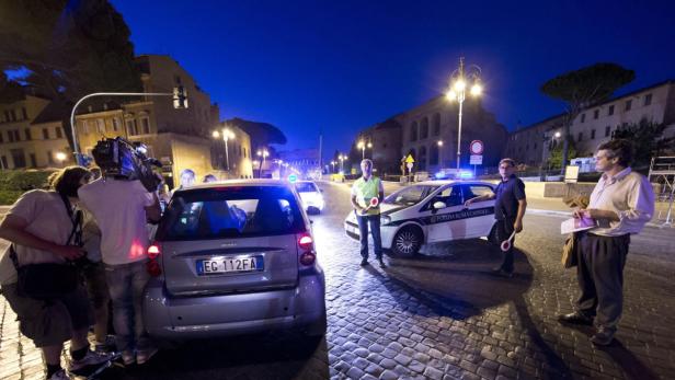 Ein Filmteam dreht eine Szene mit Polizeiautos in einer italienischen Stadt.