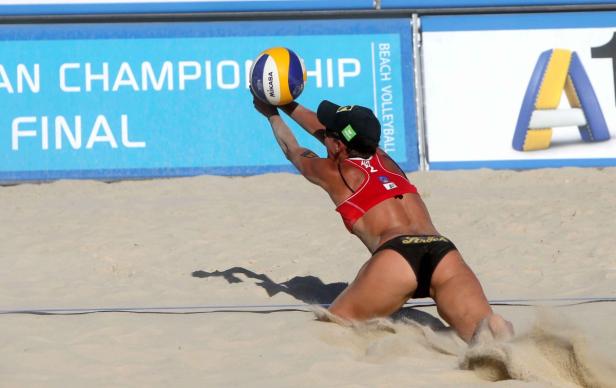 Eine Beachvolleyballspielerin baggert den Ball im Sand.