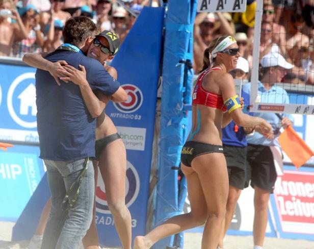 Eine Beachvolleyballspielerin umarmt ihren Trainer nach einem Spiel am Strand.