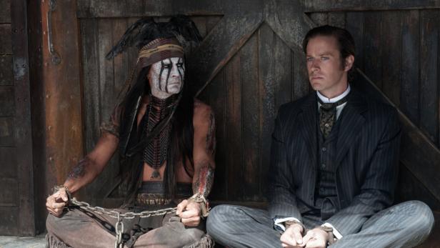 Tonto und John Reid, gefesselt, sitzen vor einer Holzwand.