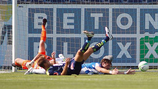 Mehrere Fußballspieler liegen nach einem Spielzug vor dem Tor auf dem Rasen.